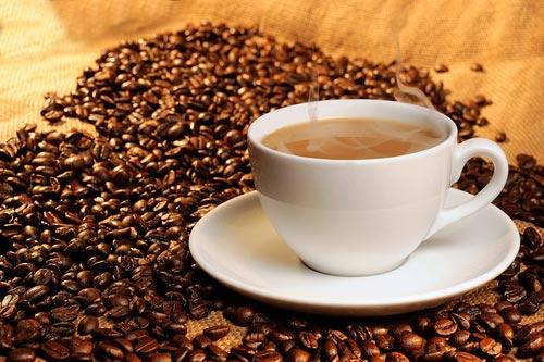 Чашечка кофе на деревянном столе на фоне зерен