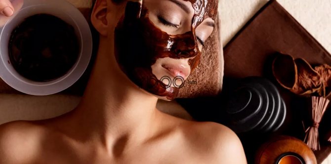 A girl is given a mask of cocoa powder on her face.