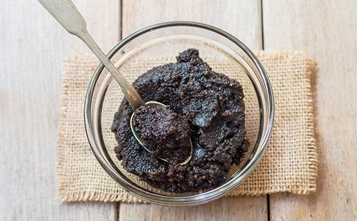 Homemade coffee scrub in a cup on a simple napkin
