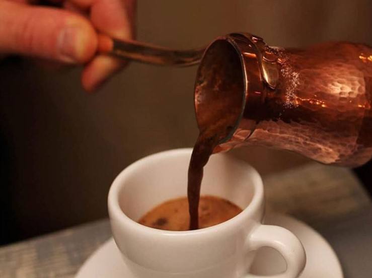 Turkish coffee is poured into a cup