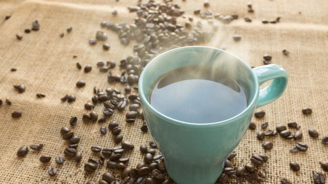 Кофе в чашке и рассыпанные на столе зерна кофе